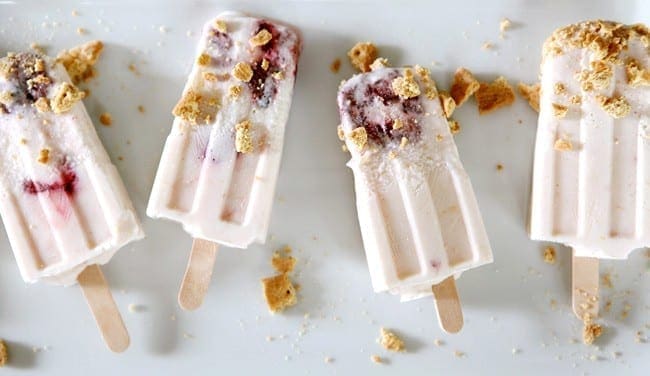 Four Roasted Strawberry Cheesecake Pops on a white platter with graham cracker sprinkles