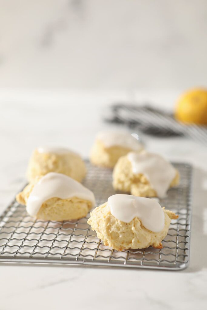Lemon Drop Cookies, topped with a lemon glaze, sit on a metal tray