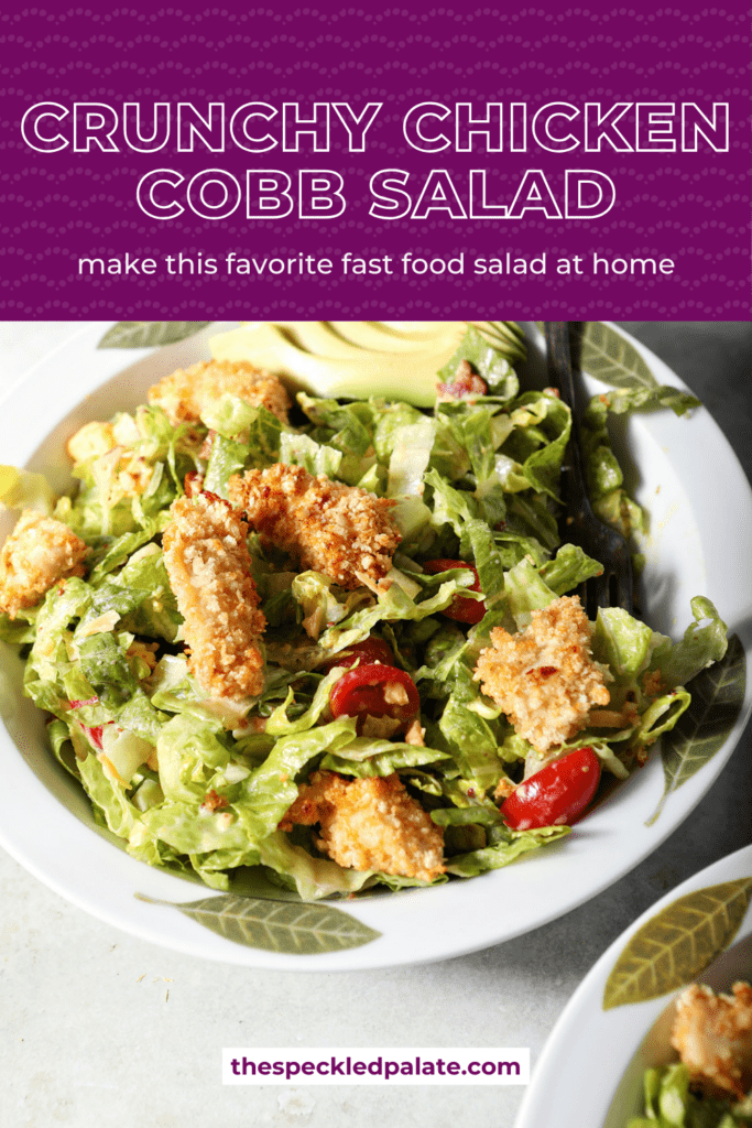 close up of a bowl of crispy chicken cobb salad with a fork in it on a green surface with the text crunchy chicken cobb salad make this favorite fast food salad at home